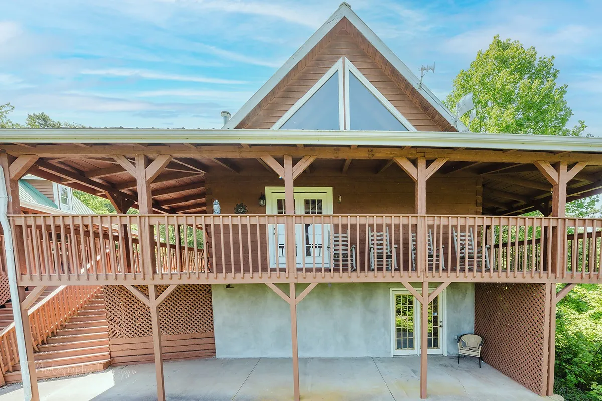 A wide balcony with rocking chairs, exposed wooden beams, and a large triangular window, offering space for socializing, morning coffee, and sunset views.