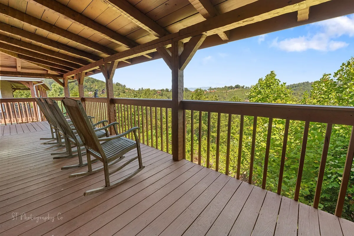 A serene porch with rustic rocking chairs overlooking distant mountains and lush landscape, inviting guests to relax, chat, or reflect while immersed in nature.