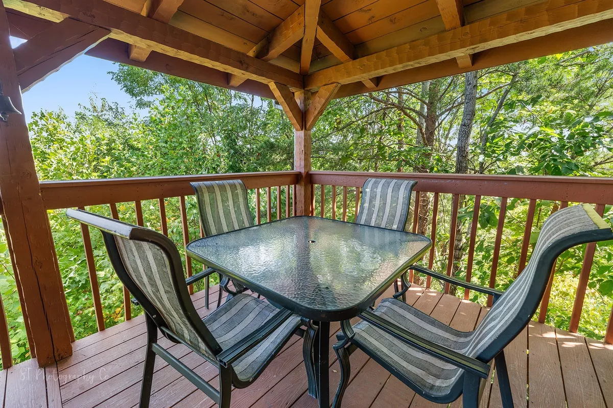This exterior shot features a wooden gazebo structure with a glass table and striped chairs surrounded by lush greenery, creating an inviting spot for outdoor dining or relaxing after a day of fun.